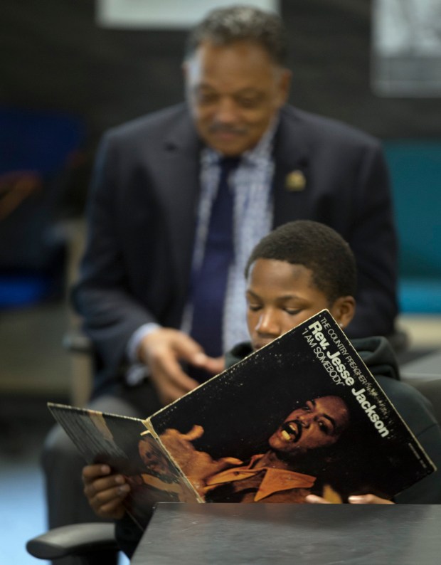 A student looks through the liner notes of Rev. Jesse Jackson's 1971 album "I Am Somebody," while the noted civil rights activist looks on during his visit to the African American Male Achievement Manhood Development Class at Montera Middle School in April of 2016, in Oakland. (D. Ross Cameron/Bay Area News Group)