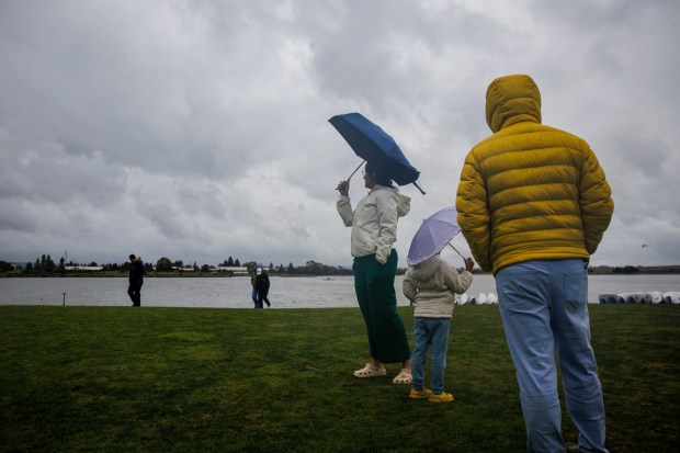 Chandani Chordiya, left, of Milpitas, her husband, Rohan, right, and their daughter, Sanshrita, 5, visit Shoreline Lake in Mountain View, Calif., as a storm soaks the Bay Area on Monday, Feb. 16, 2026. Chandani said the rain brings back fond memories of dancing in the rain as a child in India. (Dai Sugano/Bay Area News Group)