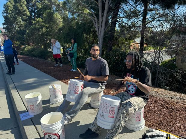12:24: A pair of buskers are entertaining people in line playing drums with buckets as fans enter for Super Bowl 60 in Santa Clara Feb. 8, 2026.. (Sal Pizarro/Bay Area News Group)