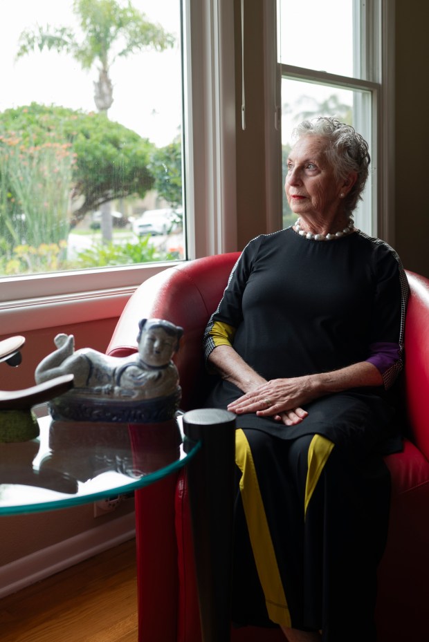 Sonia Ancoli-Israel poses in her living room next to a selection of pillows from her personal collection. (McKenzie Patterson / For The San Diego Union-Tribune)