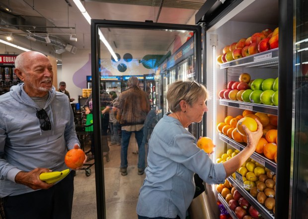  Some of the first customers during the grand opening at SunCoast Market Co-op, Kenny Mischel, left, of Imperial Beach looks on, as Carolyn Carswell, right, also of Imperial Beach, selects fruit at only the second Co-op market to open in San Diego County in the last 55 years, Saturday January 31, 2026, in Imperial Beach, California. (Howard Lipin / For The San Diego Union-Tribune)