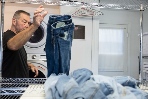 Steve Osterhage moves dry jeans out of the dryer at his at home laundry business in San Diego, Tuesday, Jan. 20, 2026. (Zoë Meyers / For The San Diego Union-Tribune)