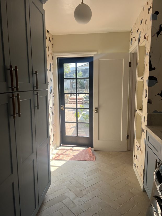 The new laundry area makes smart use of a small space near a backdoor entrance, with full-size cupboards to store supplies. Carmen Coutts had a tile floor laid in a herringbone pattern.  (Daughters of Design)