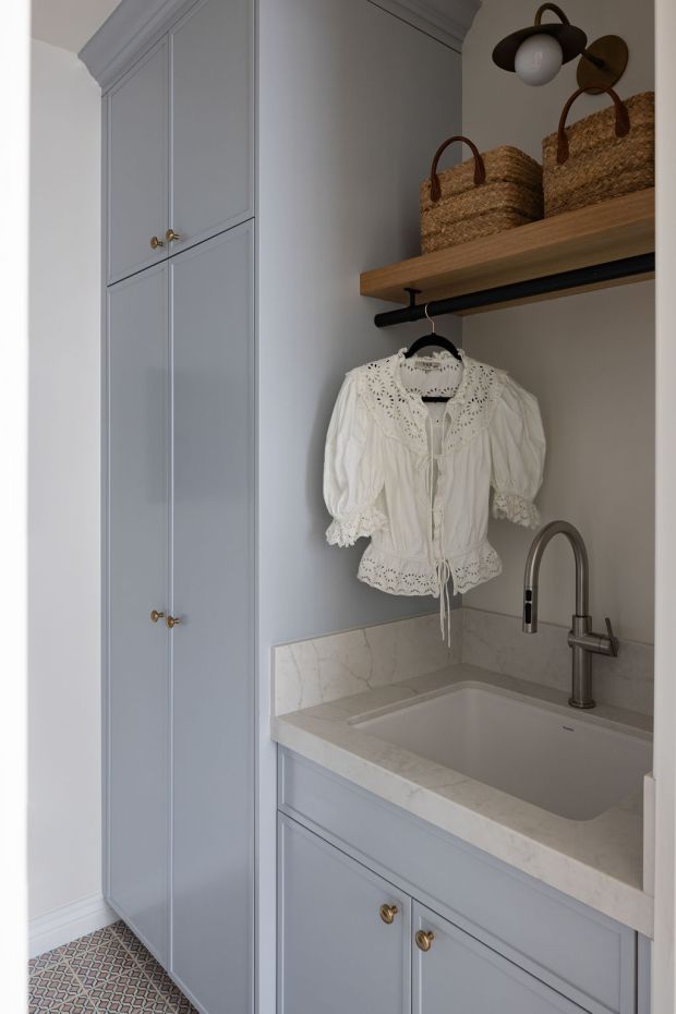 A laundry room by South Harlow Interiors incorporates a hanging rod above the sink for air drying clothes. (Nader Essa)