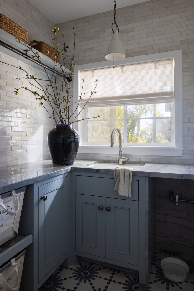 A laundry room by South Harlow Interiors includes a pot filler in the cupboards below for the dog bowl beneath it. (Nader Essa)