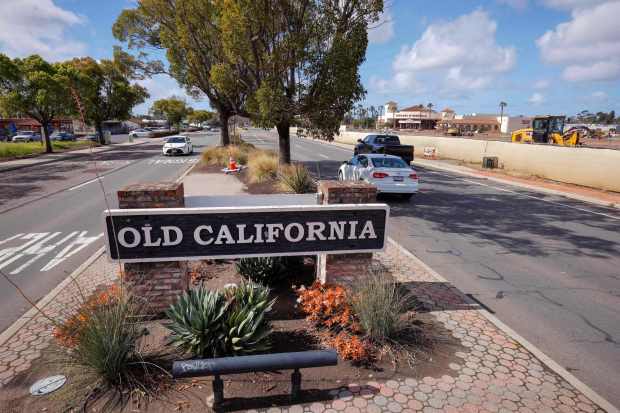 2/18/2026_San Marcos, CA_A sign for the former site of Old California Restaurant Row is in the median strip of San Marcos Blvd. in this view looking west. The site across the westbound lanes at right is now under construction for residential and commercial buildings. In the distance along the west end of the property is Edwards Cinemas theaters. (Charlie Neuman / For The San Diego Union-Tribune)