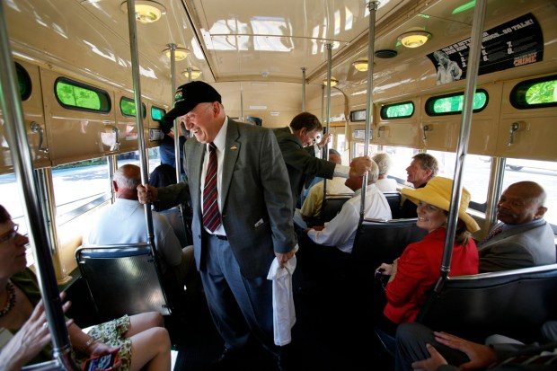 Harry Mathis, standing, then chair of the MTS board, chats with riders on a restored 1949 vintage trolley's inaugural run on August 19, 2011, in San Diego. (Peggy Peattie / For The San Diego Union-Tribune)