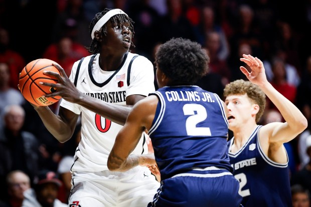 Magoon Gwath #0 of San Diego State looks to pass against Mj Collins #2 and Mason Falslev #12 of Utah State during their game at Viejas Arena on Wednesday, Feb. 25, 2026 in San Diego, California. (Meg McLaughlin / The San Diego Union-Tribune)