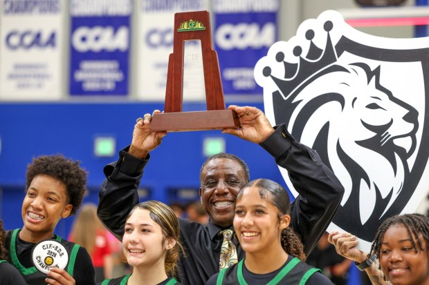 SAN MARCOS, CA - February 27, 2026: Lincoln head coach James Townsend holds up the trophy after his players as they celebrate beat La Costa Canyon 60-47 for the CIF Division 2 girls basketball championship at California State University San Marcos in San Marcos on Friday, February 27, 2026. (Hayne Palmour IV / For The San Diego Union-Tribune)