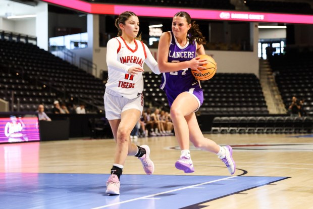 Carlsbad High's Mallory Huhn drives past Imperial High's Elynna Jimenez during the CIF Division 1 championship at Frontwave Arena in Oceanside on Saturday, Feb. 28, 2026. The Lancers defeated the Tigers 54-50. (Kristian Carreon / The San Diego Union-Tribune)