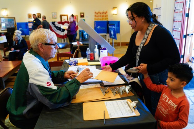 Ivon Bardales of Chula Vista and her two children, Brandon and Vanessa, checked in with election worker John Volland at the polling location in City Hall on Tuesday, Nov. 4, 2025.   (Nelvin C. Cepeda / The San Diego Union-Tribune)
