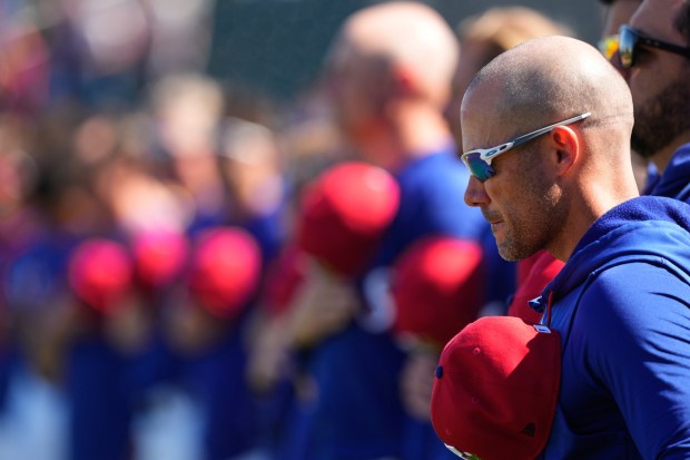 Texas Rangers manager Skip Schumaker stands for the national anthem before a spring training baseball game against the Colorado Rockies, Sunday, Feb. 22, 2026, in Surprise, Ariz. (AP Photo/Charlie Riedel)