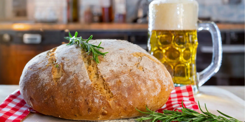 A loaf of bread sits beside a glass stein full of beer