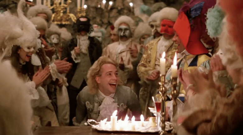 A still image from the film Amadeus, showing Mozart at the piano at a party