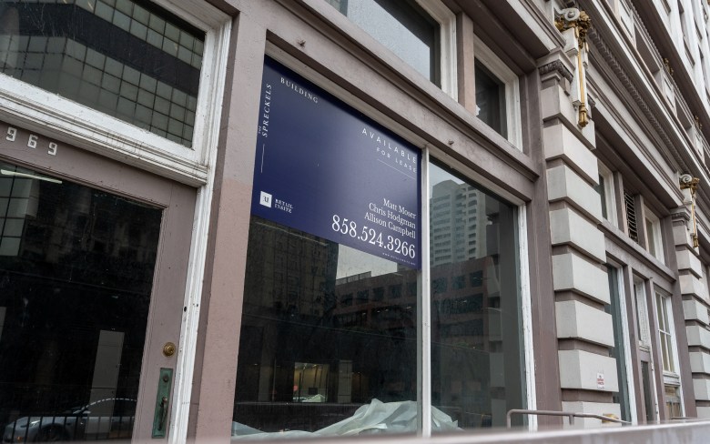 A real estate company's "Available for lease" sign hangs in the window of an unused building.