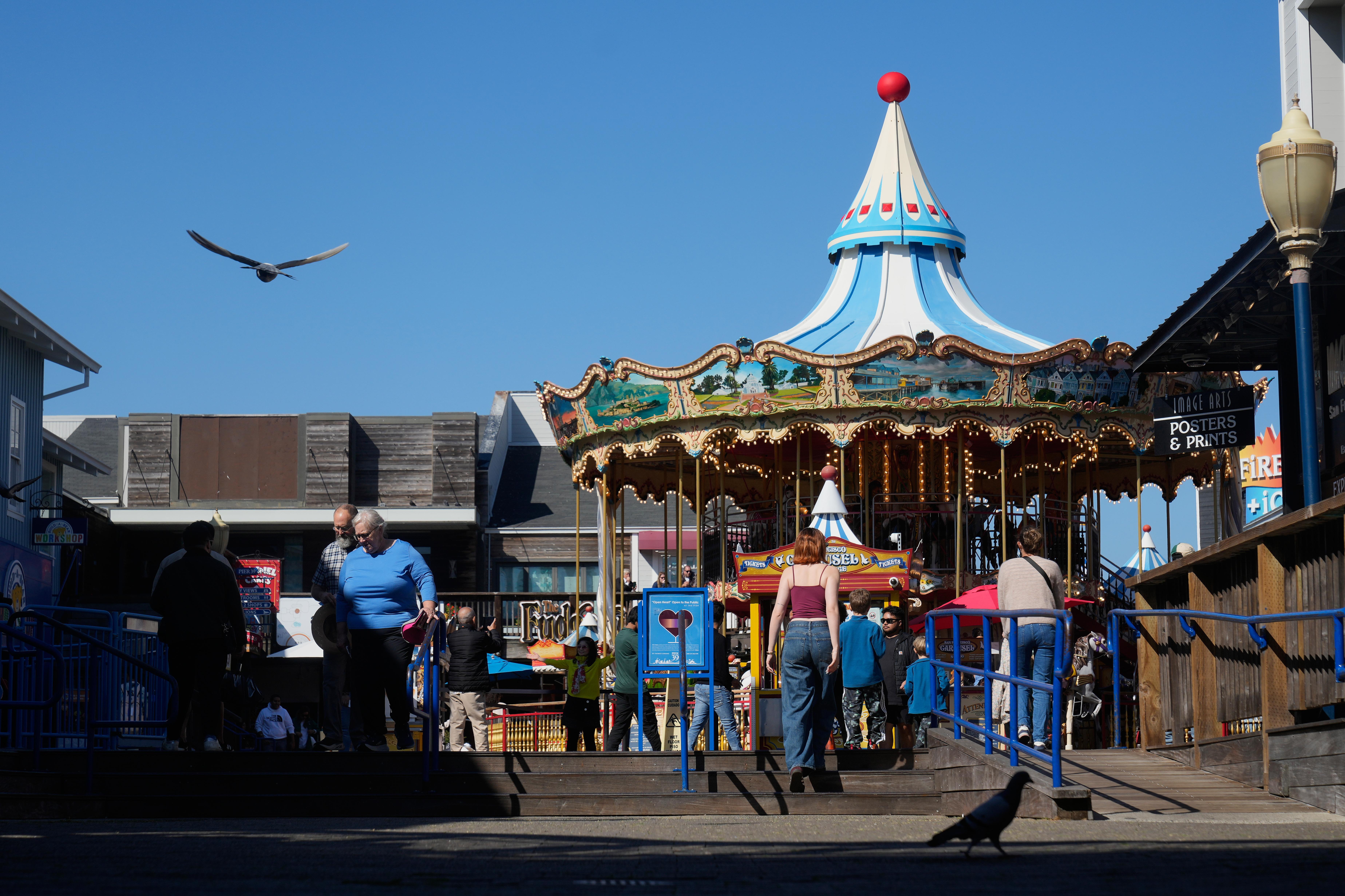 People walk in front of the carousel at Pier 39...