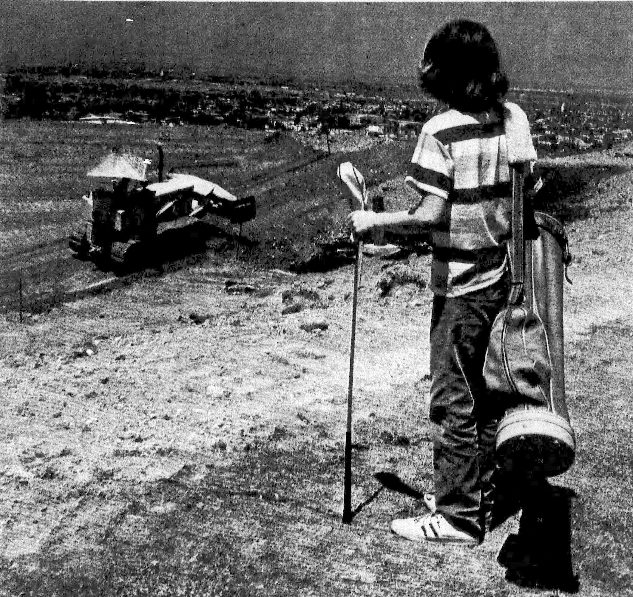 An unidentified young golfer looks out at new course construction...