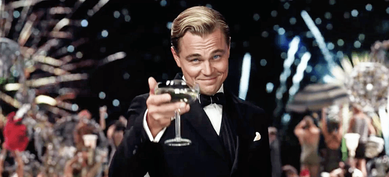 Still from the film of The Great Gatsby, showing a man raising a glass of Champagne at a party