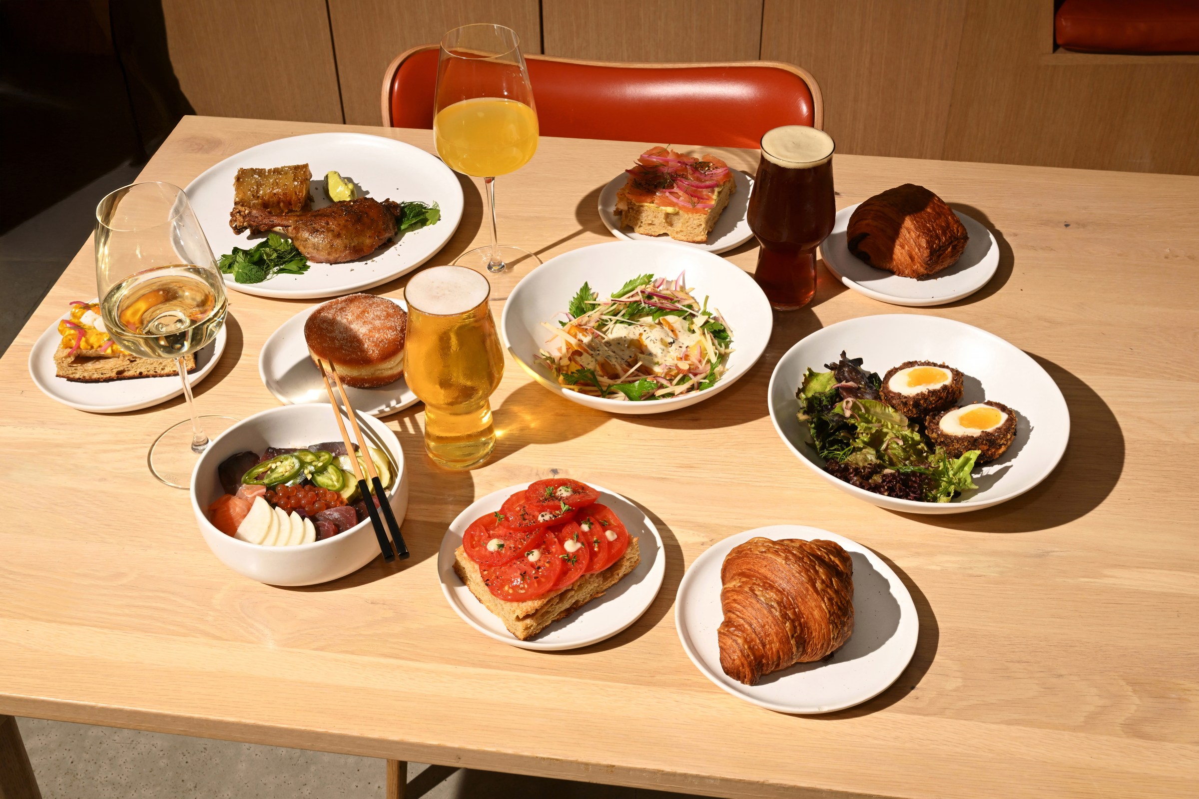Overhead shot of a spread of pastries and beer on a wood table at Tomat.