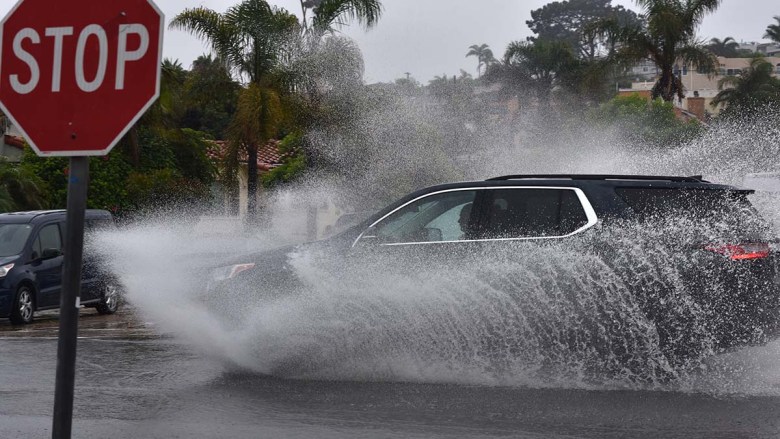 A car splashes through flooded streets in Ocean Beach during Tropical Storm Hilary. Photo by Chris Stone