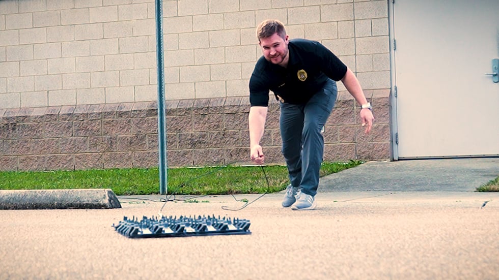 Captain Ryan Henry deploying a spike strip outside the Pass Christian Police Department.