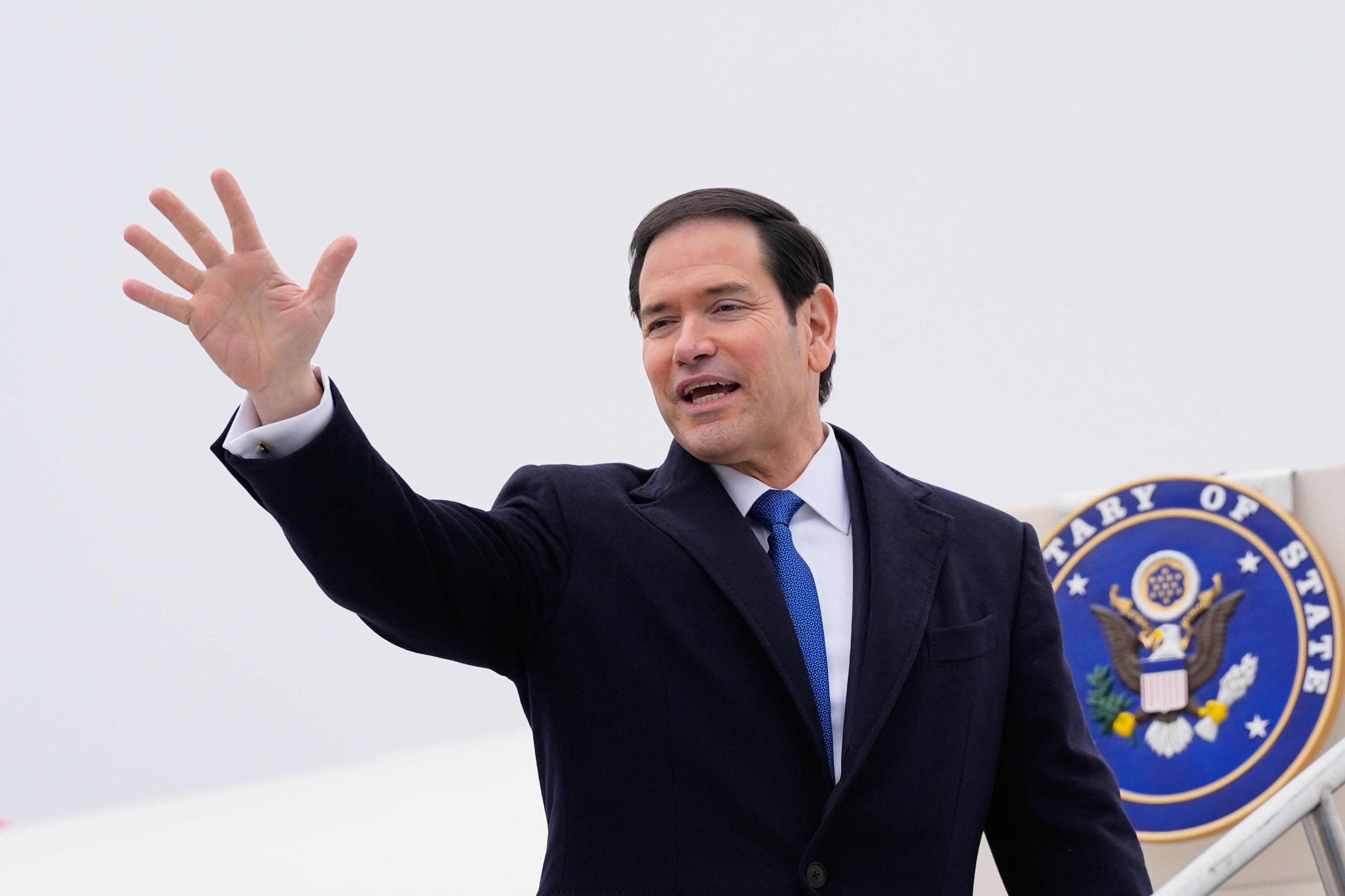 U.S. Secretary of State Marco Rubio waves as gets on a plane.