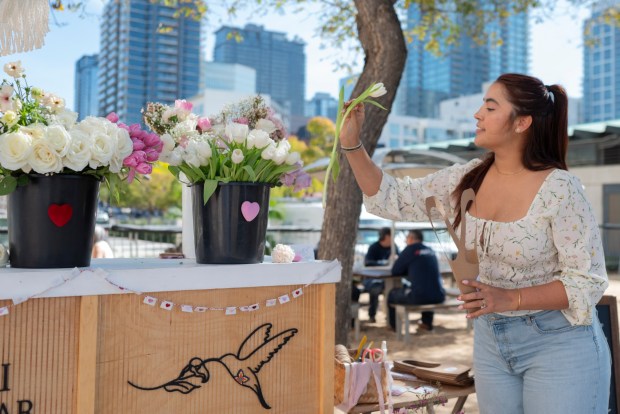 Jessica Valenzuela selects flowers for a bouquet at a Colibri Flower Studio pop-up stand outside the San Diego County Administration Center on Feb. 14, 2026, where newlyweds could create and purchase floral arrangements. (McKenzie Patterson / For The San Diego Union-Tribune)
