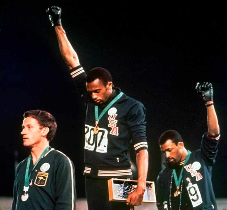 FILE - In this Oct. 16, 1968, file photo, Australian silver medalist Peter Norman, left, stands on the podium as Americans Tommie Smith, center, and John Carlos raise their gloved fists in a human rights protest. Australian Olympic Committee (AOC) aw