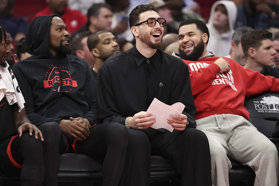 Dec 27, 2025; Houston, Texas, USA; Houston Rockets center Alperen Sengun (middle) laughs on the bench with forward Kevin Durant (left) and guard Fred Vanvleet (right) during the second half against the Cleveland Cavaliers at Toyota Center. Mandatory Credit: Troy Taormina-Imagn Images