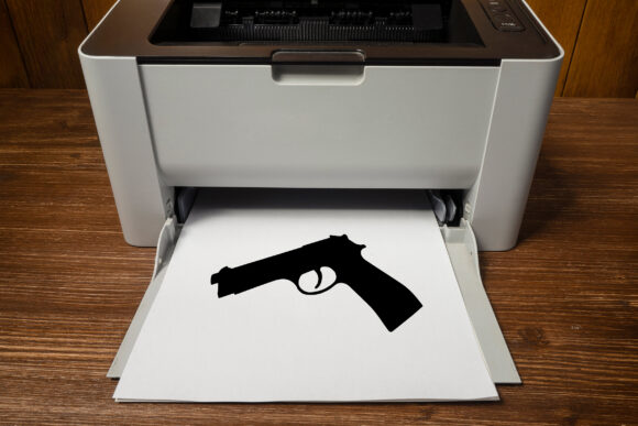 A gun printed on a sheet of paper exiting the printer