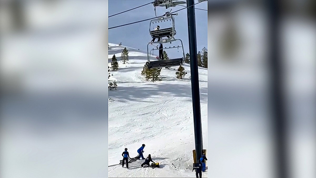 Wide view shows ski patrol positioning safety net below chairlift