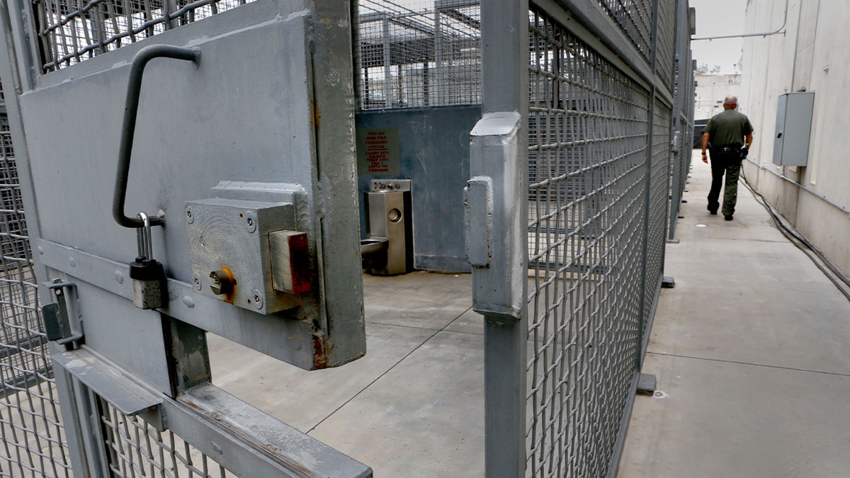 A grid of small, caged outdoor enclosures sits beside a prison building in Represa, California.