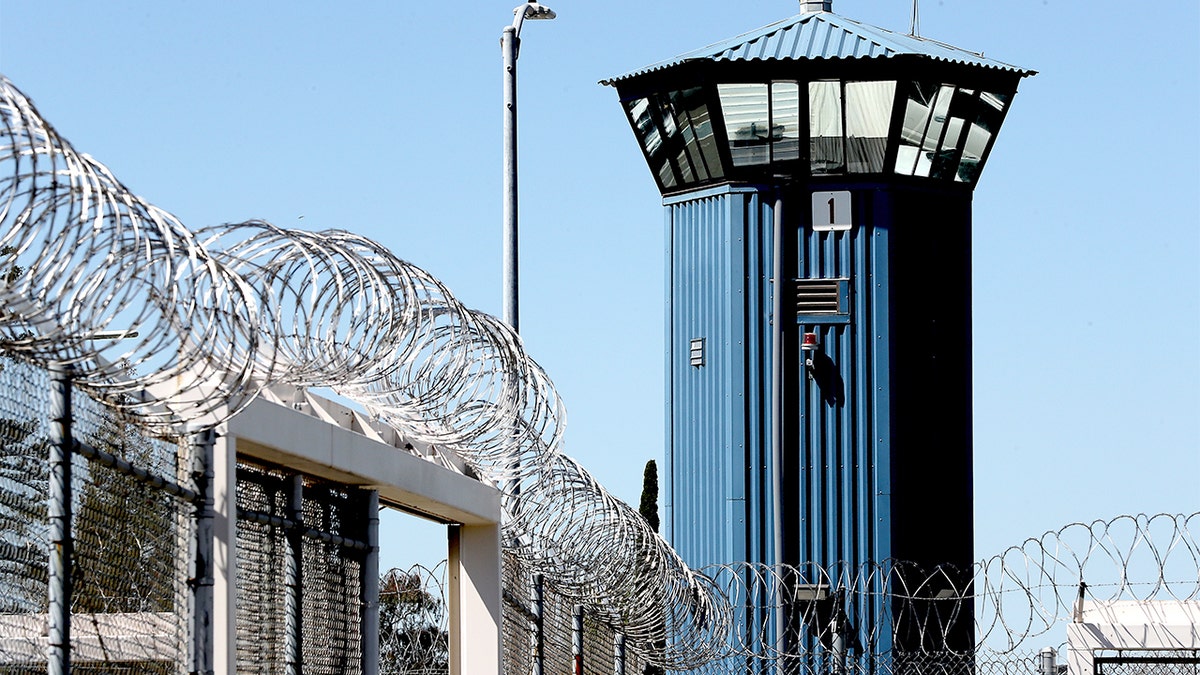 Coils of razor wire line a tall security fence outside a prison housing unit in Represa, California.