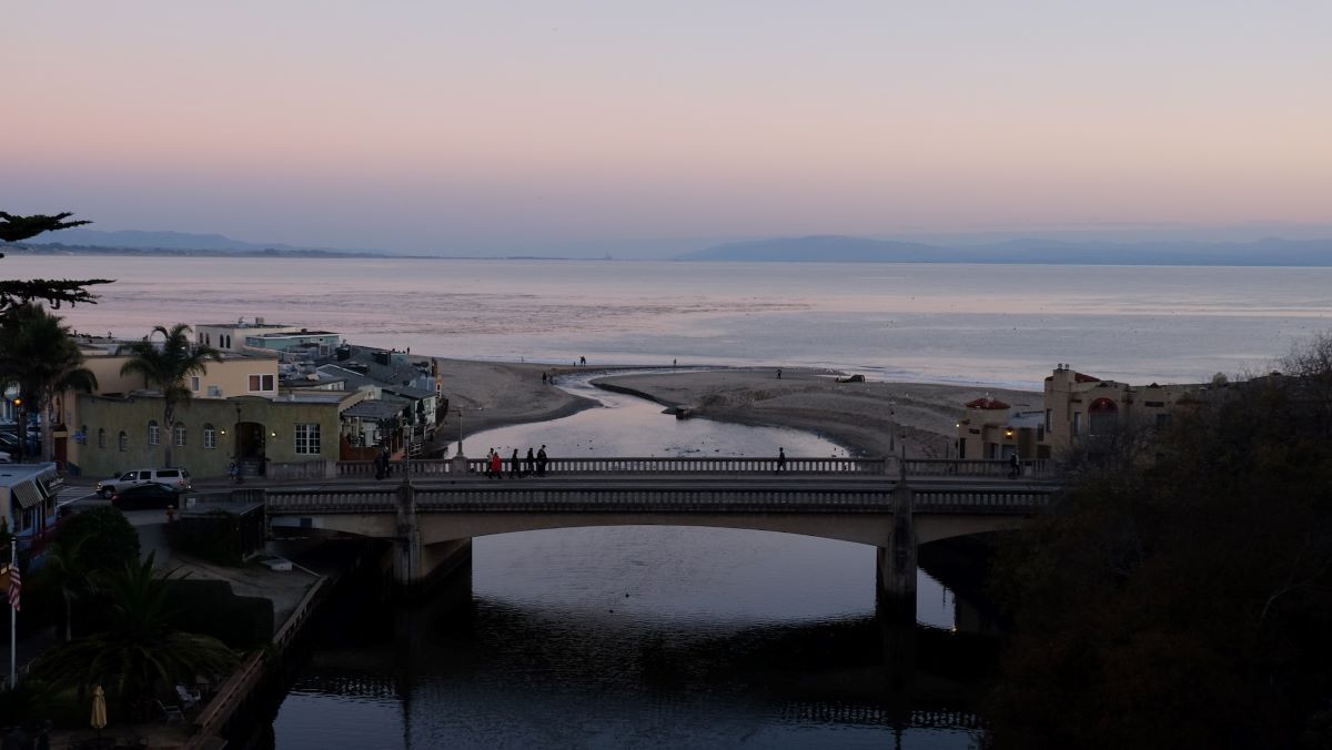 People cross a bridge at sunset in Capitola.