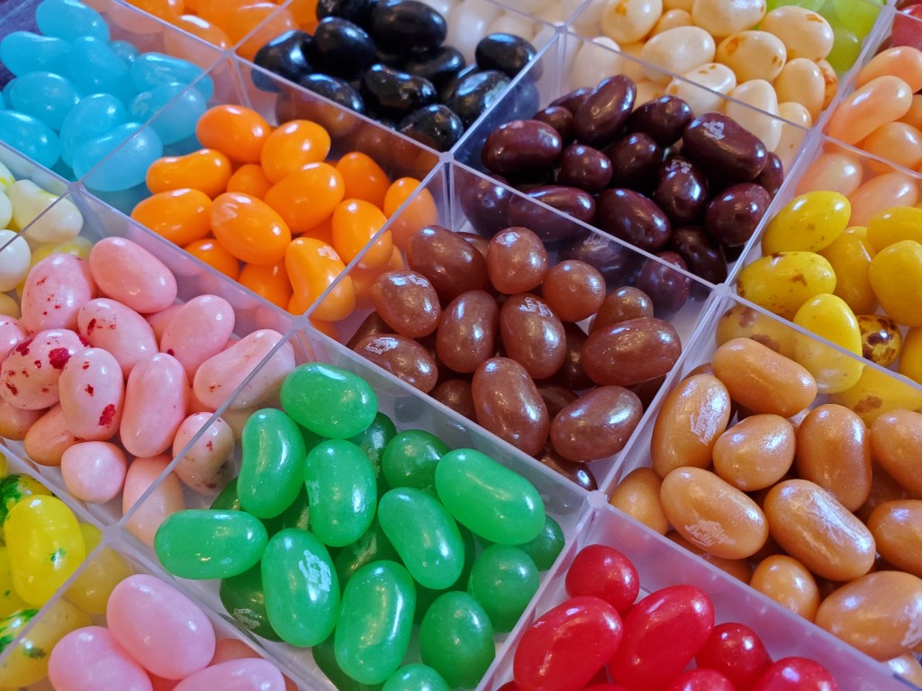 Close-up of multicolored Jelly Belly jelly beans in a clear divided container.