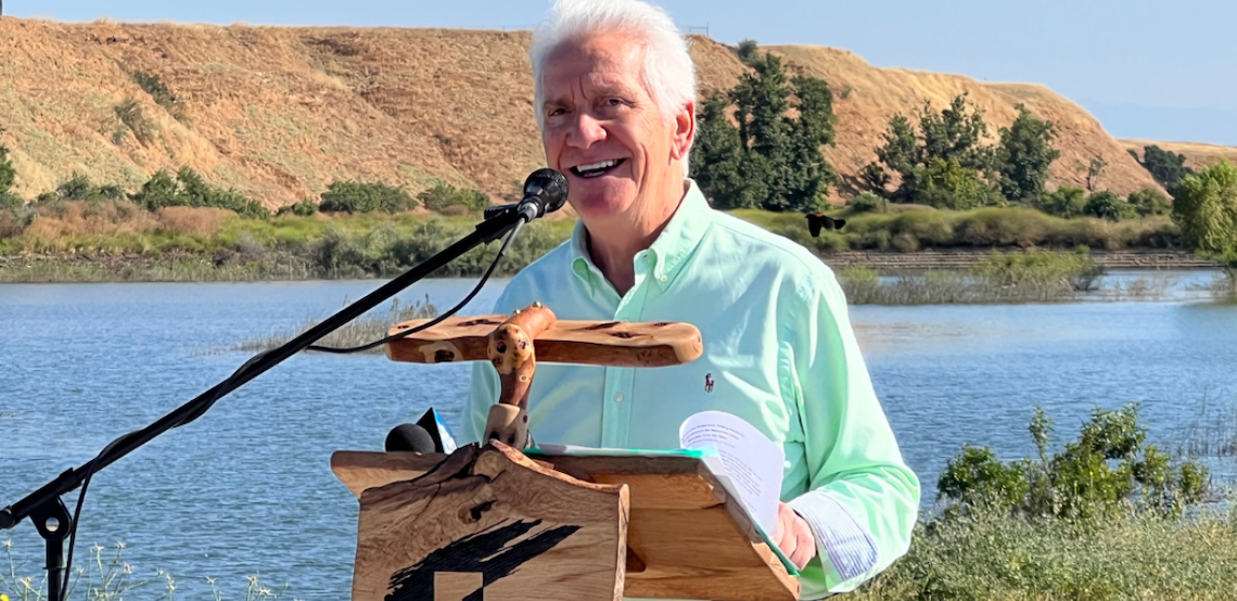 man at a podium in front of a river