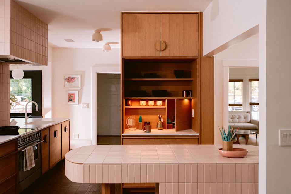 The pink island in Fireclay tile anchors the reimagined kitchen, where white oak cabinetry by Michael Grandy features integrated custom pulls. Cedar and Moss flush-mount fixtures replace generic can lights throughout the space.
