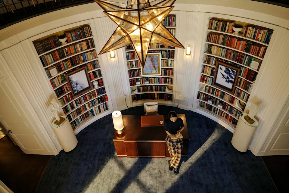 A well-appointed study featuring bookshelves and a stylish chandelier.