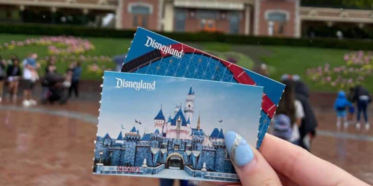 Disneyland tickets held up in front of the Main Street Railroad station.