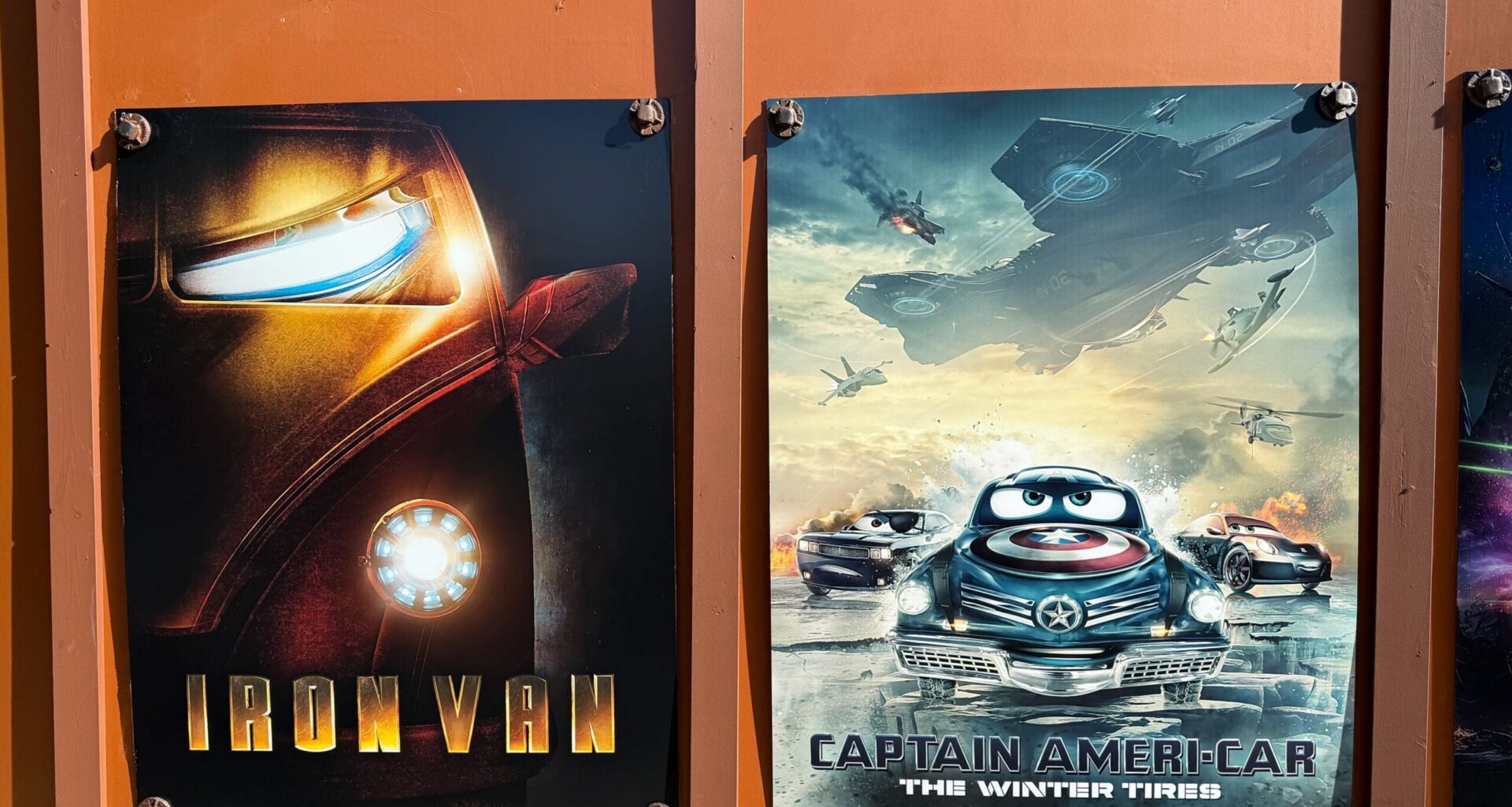 Construction walls adorned with Cars-themed Marvel parody posters on the walkway between Cars Land and Avengers Campus in Disney California Adventure