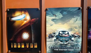 Construction walls adorned with Cars-themed Marvel parody posters on the walkway between Cars Land and Avengers Campus in Disney California Adventure