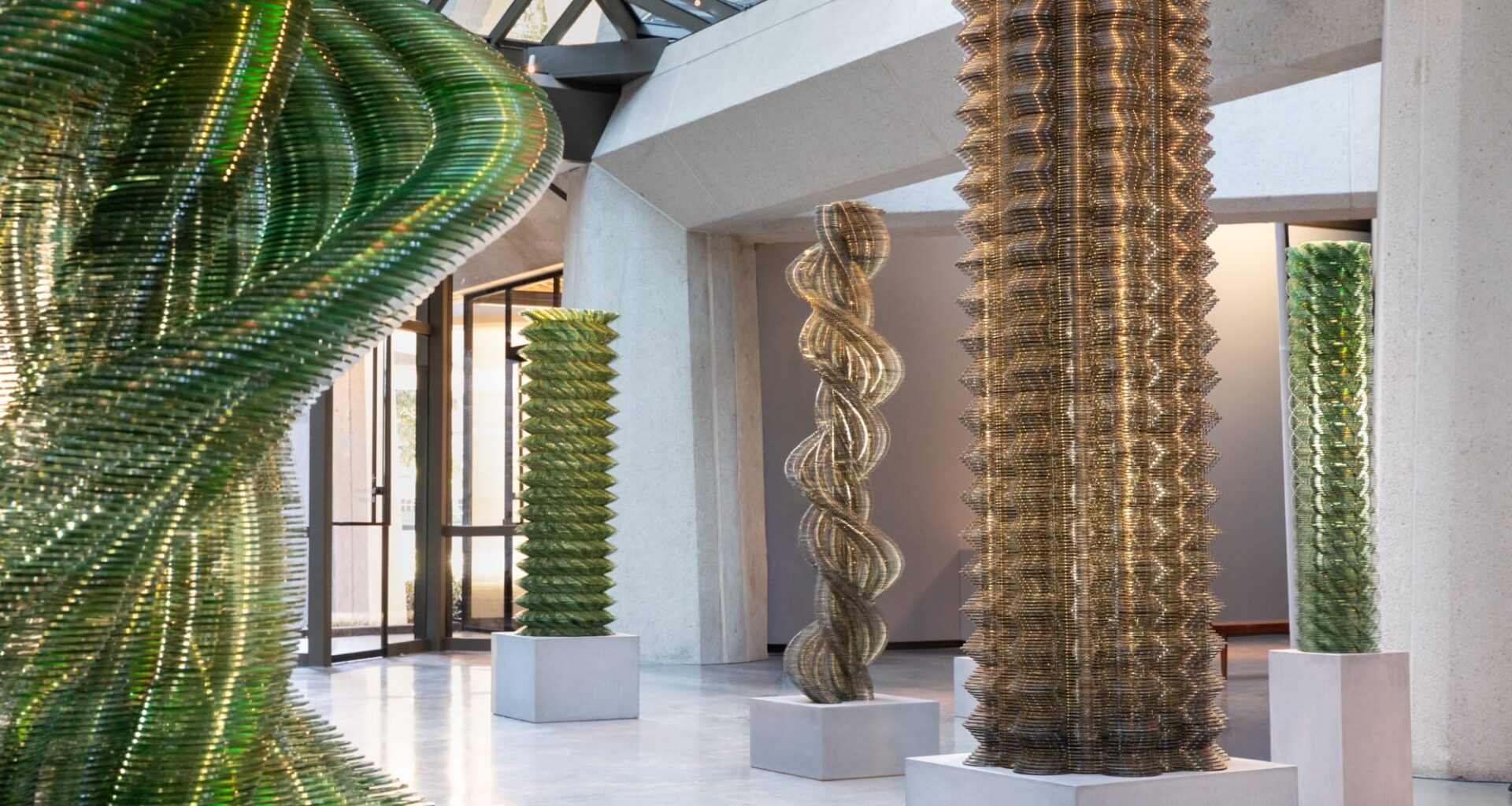 An installation view of towering artworks by Tara Donovan made of thousands of stacked CDs.
