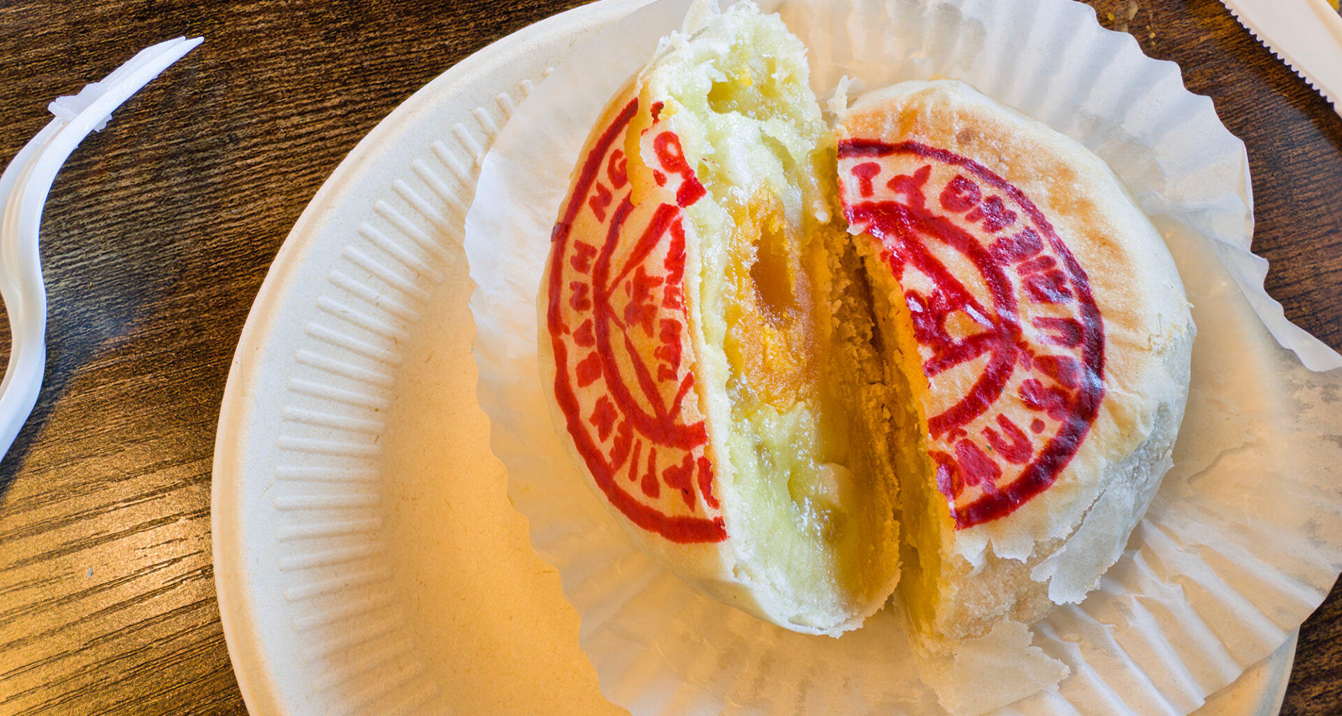 A flaky Asian pastry cut in half to reveal its durian and salted egg yolk filling.