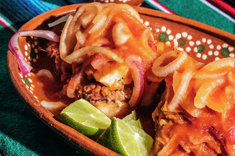 Torta ahogado from Cenaduria Elvira, laden with sauce and pickled onions. (Stephen Lam/The Chronicle)