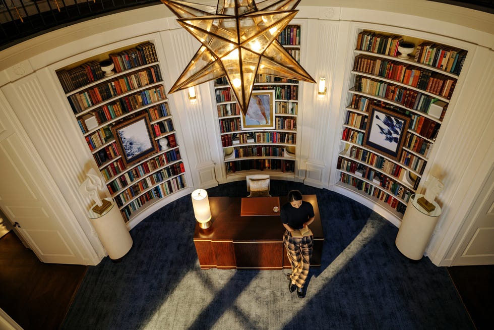 A well-appointed study featuring bookshelves and a stylish chandelier.