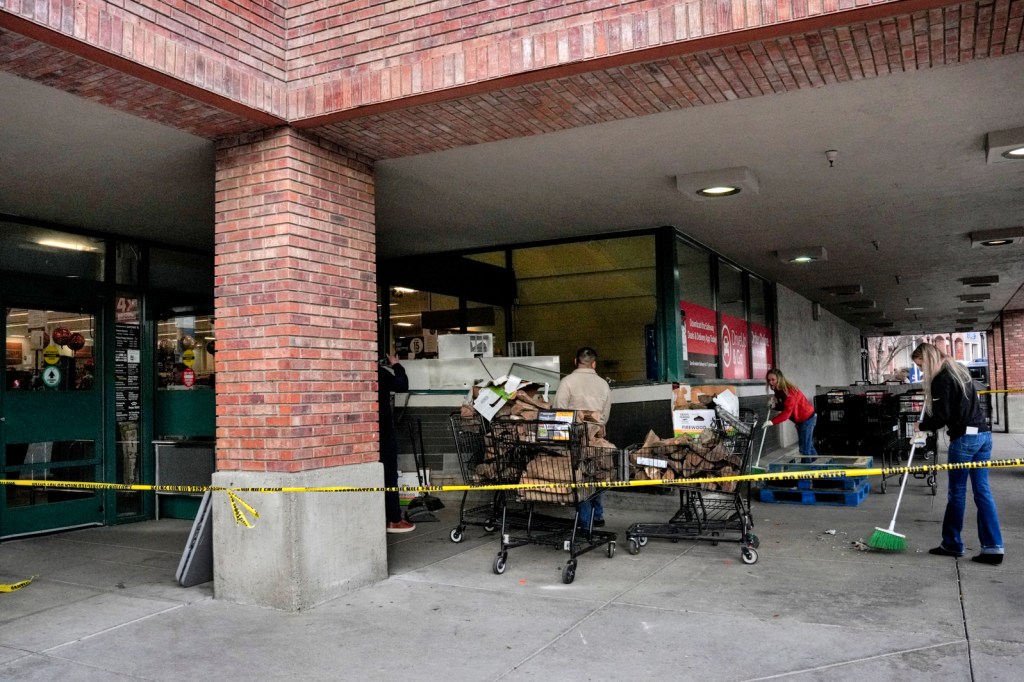 Employees clean the front of a Safeway grocery store after a vehicle crashed into the entrance.