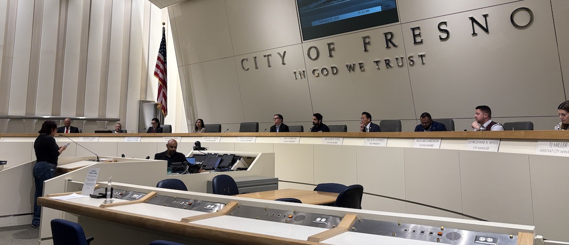 a person speaks to a city council dais gathering of members