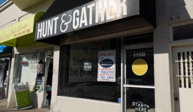 Storefront with a black awning labeled "Hunt & Gather" and several signs in the window, including "Available Platters" with contact numbers and "It all starts here SF.