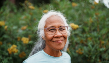Portrait of an active senior woman of Hawaiian and Chinese descent smiling directly at the camera with a look of gratitude while on a beautiful nature hike to view wildflowers.