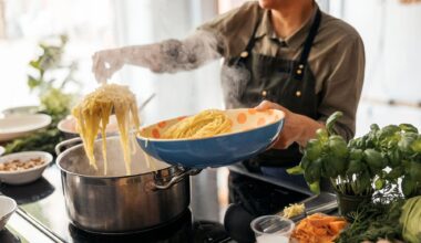 A person strains cooked spaghetti out of a steaming pot on an induction range into a serving bowl.